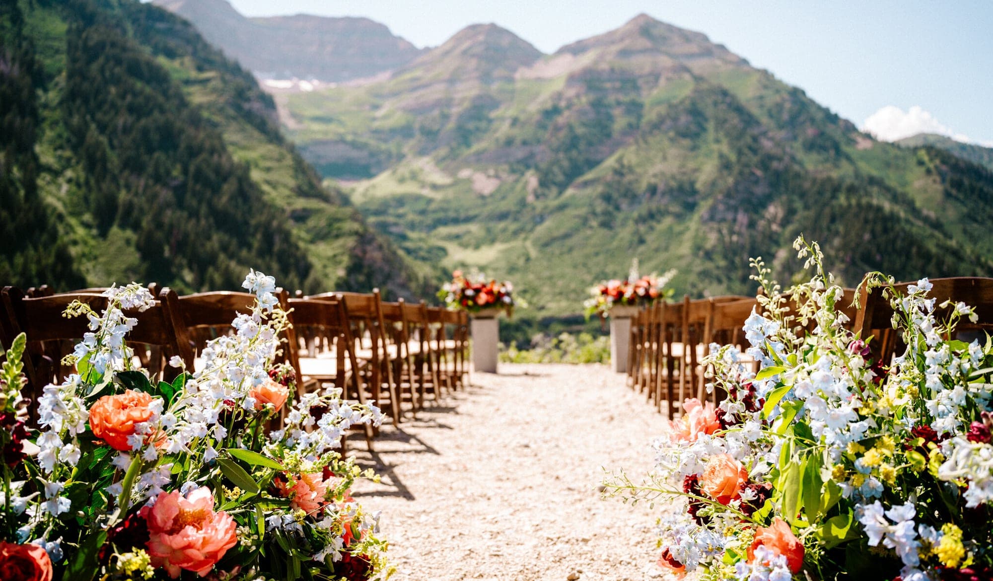 Wedding ceremony setup with chairs and flowers with mountains in the background.
