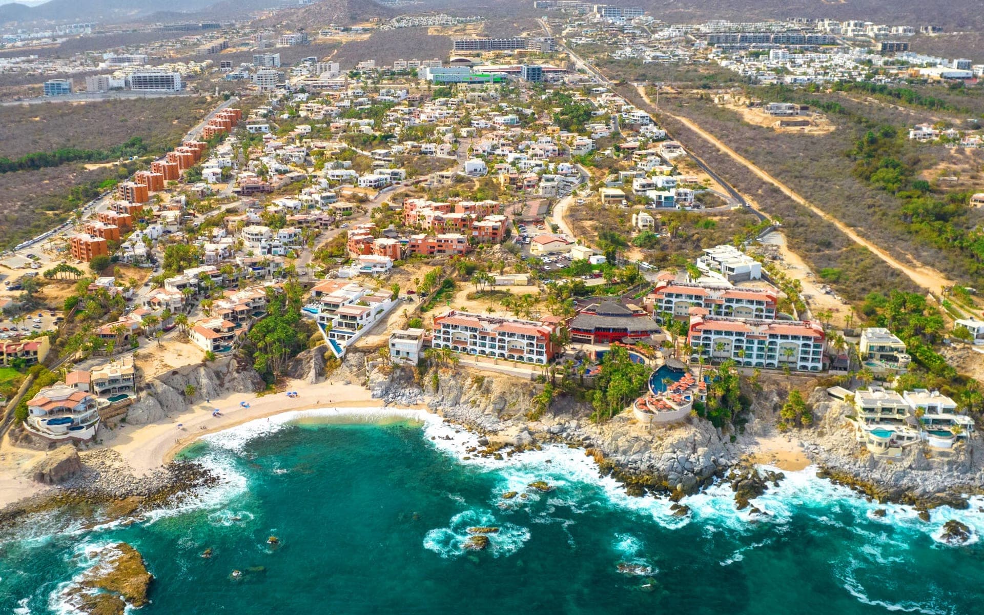 Aerial view of a coastal wedding venue with buildings and a beach.