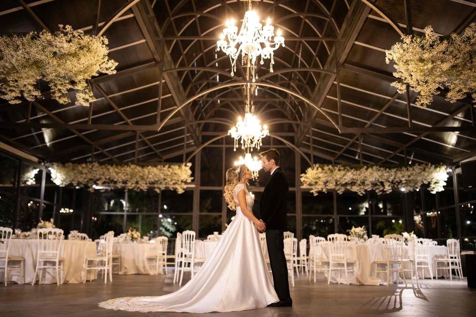 A couple stands in a conservatory set up for a wedding reception.