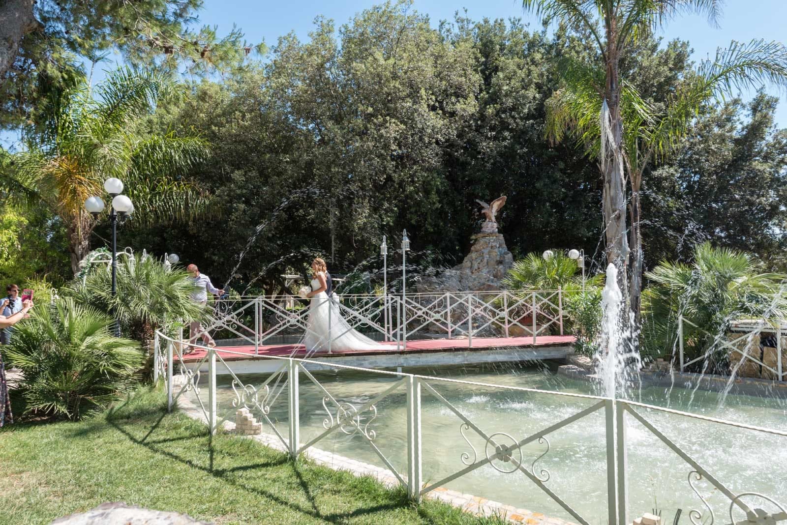Bride on a bridge over a fountain in a garden