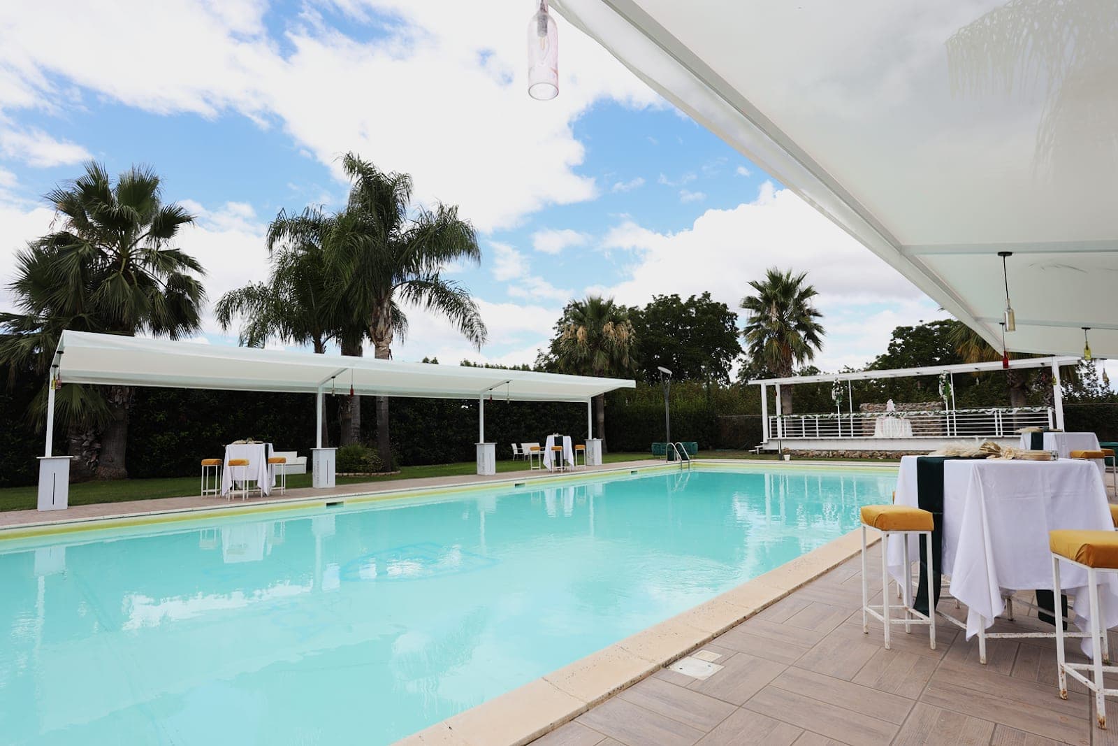 A swimming pool with tables set for an event under a canopy.