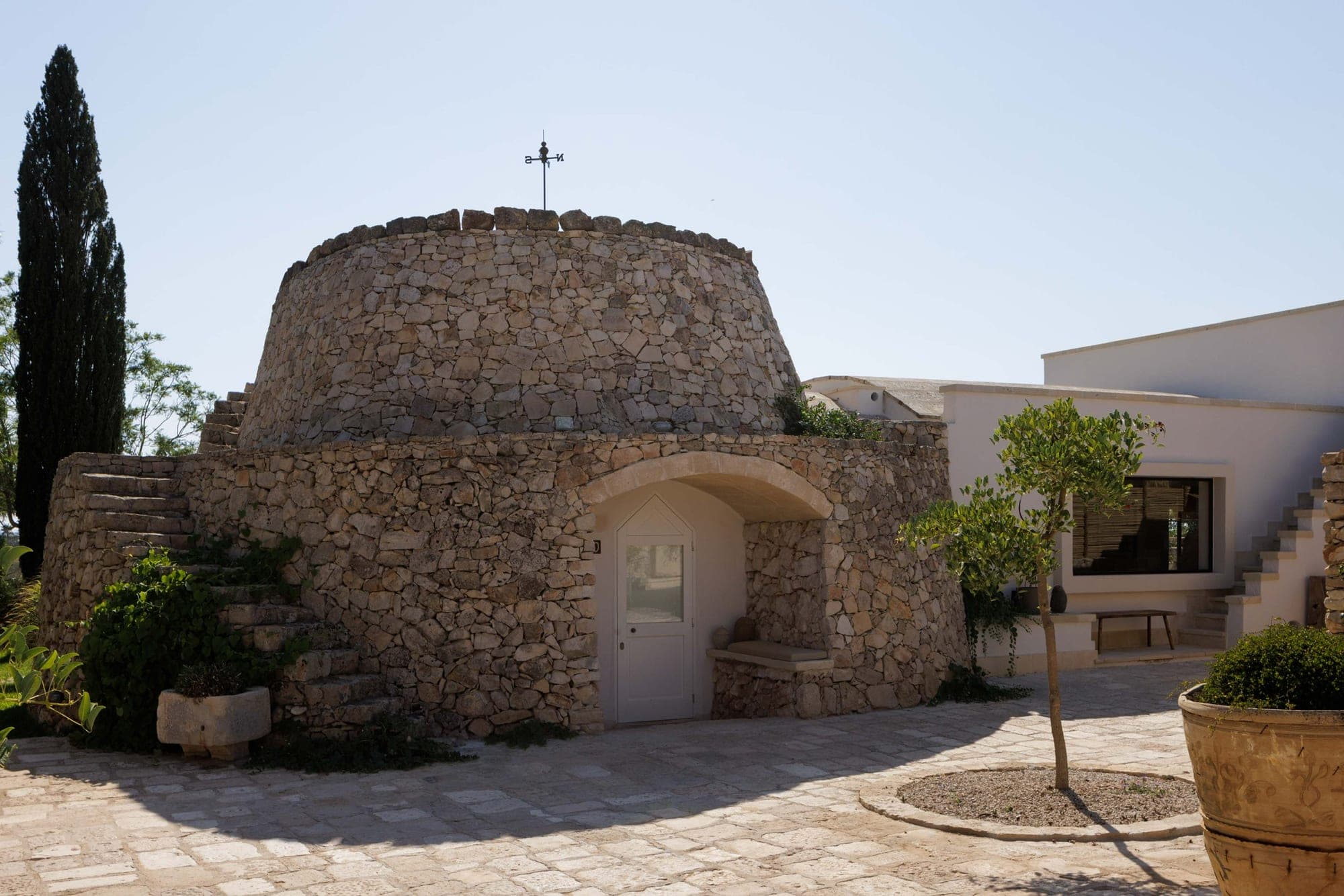 A circular stone building with a weather vane on its roof.