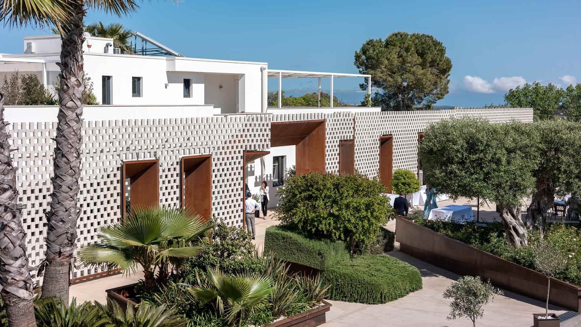 Exterior of a white building with patterned walls and lush greenery.