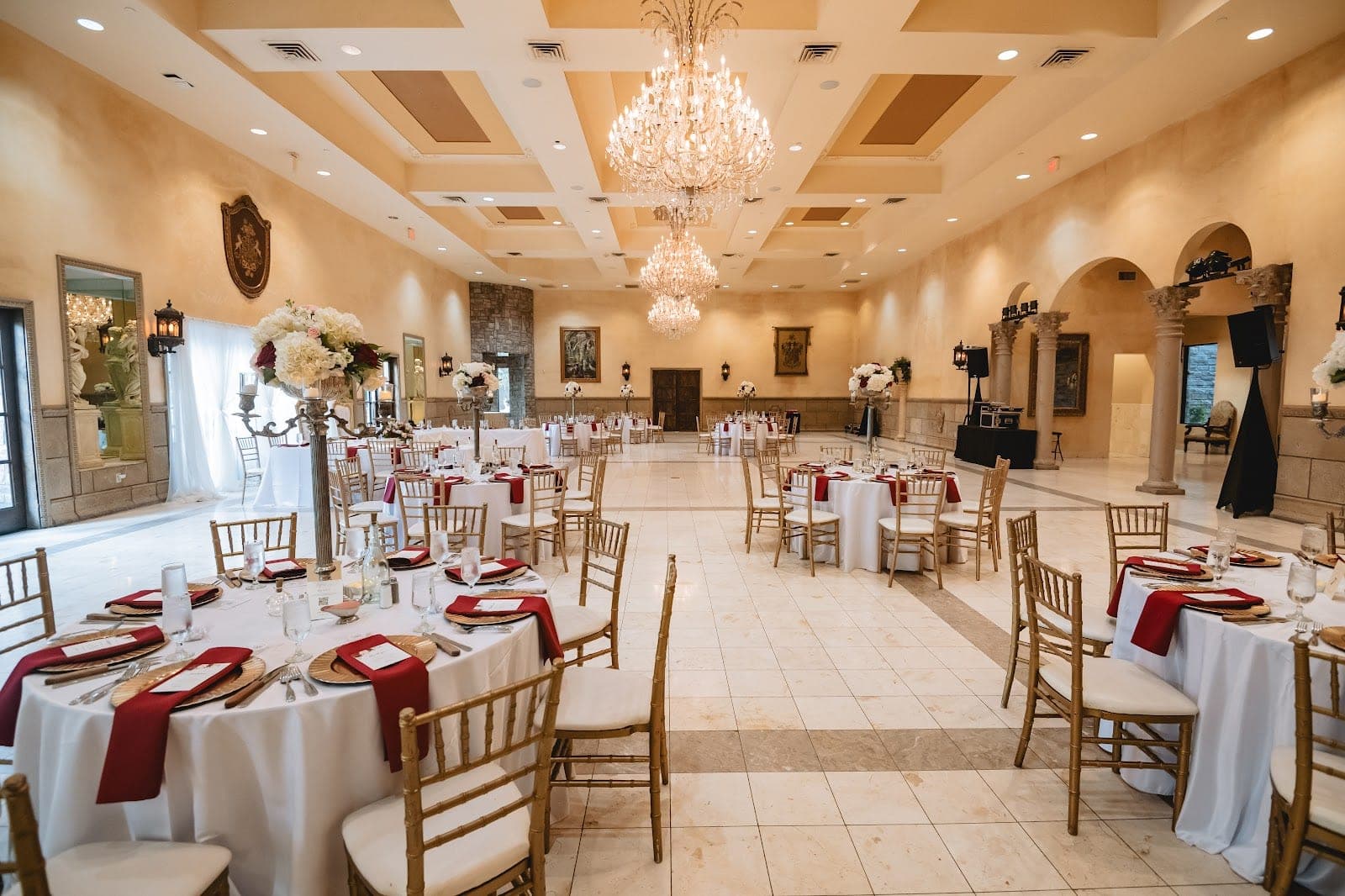 A reception hall with round tables set for a wedding.