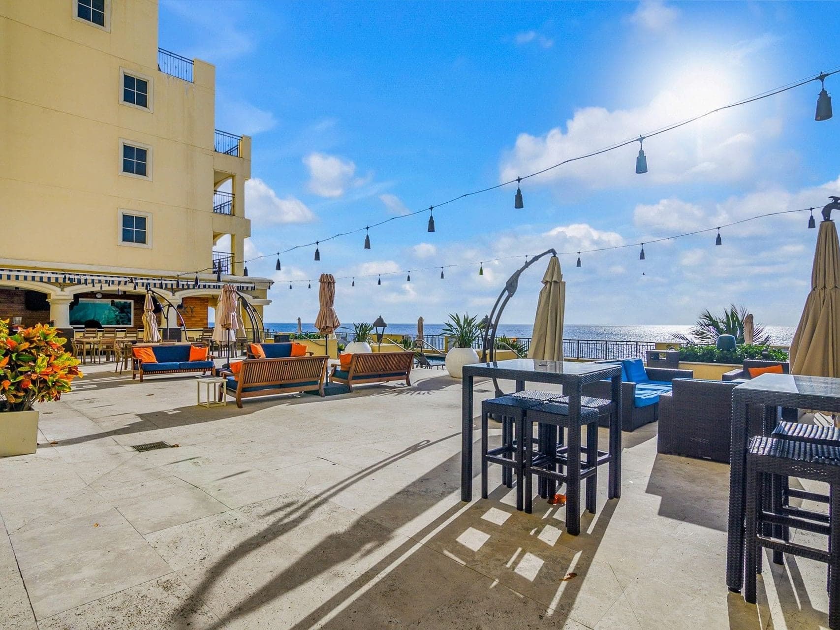 Outdoor seating area with ocean view and string lights.