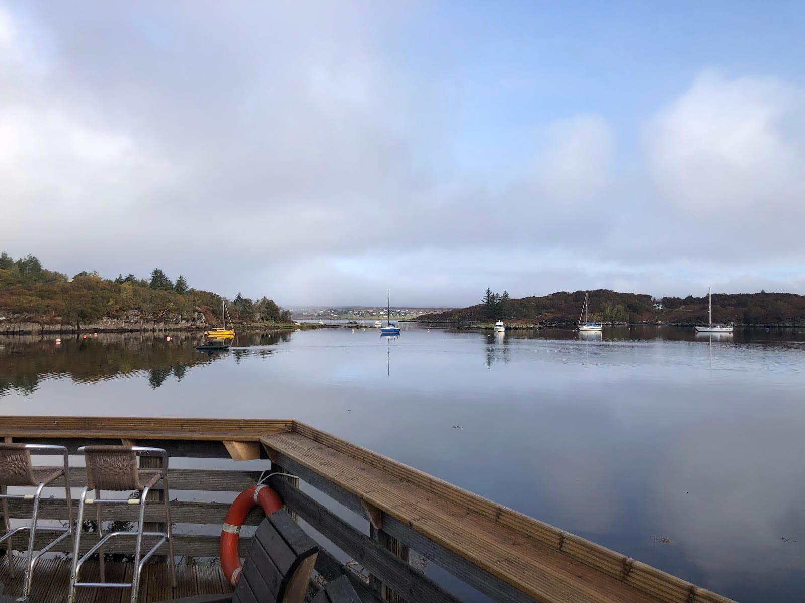 View of a bay with sailboats from a wooden deck.