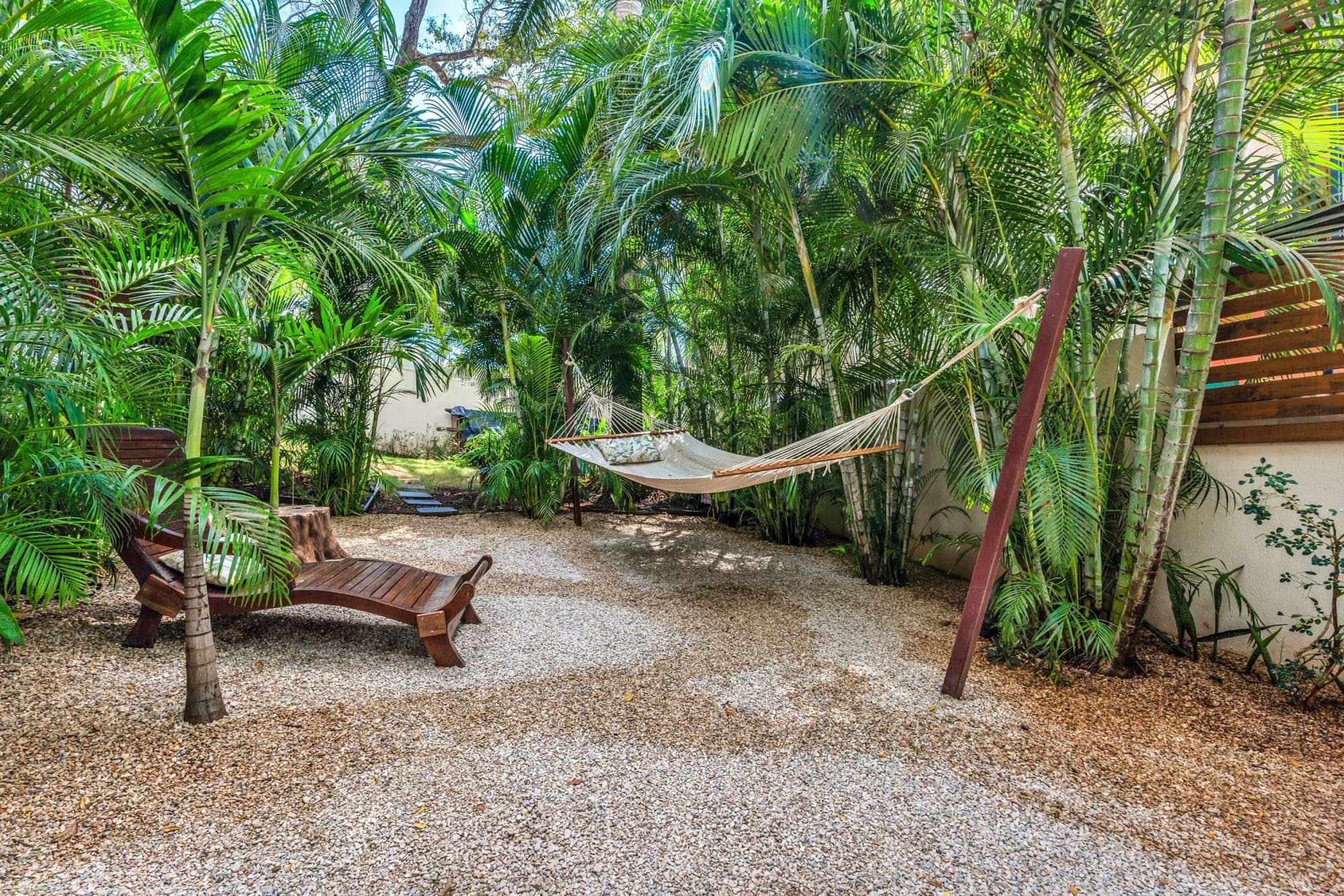 Hammock and lounge chair in a tropical garden with palm trees.