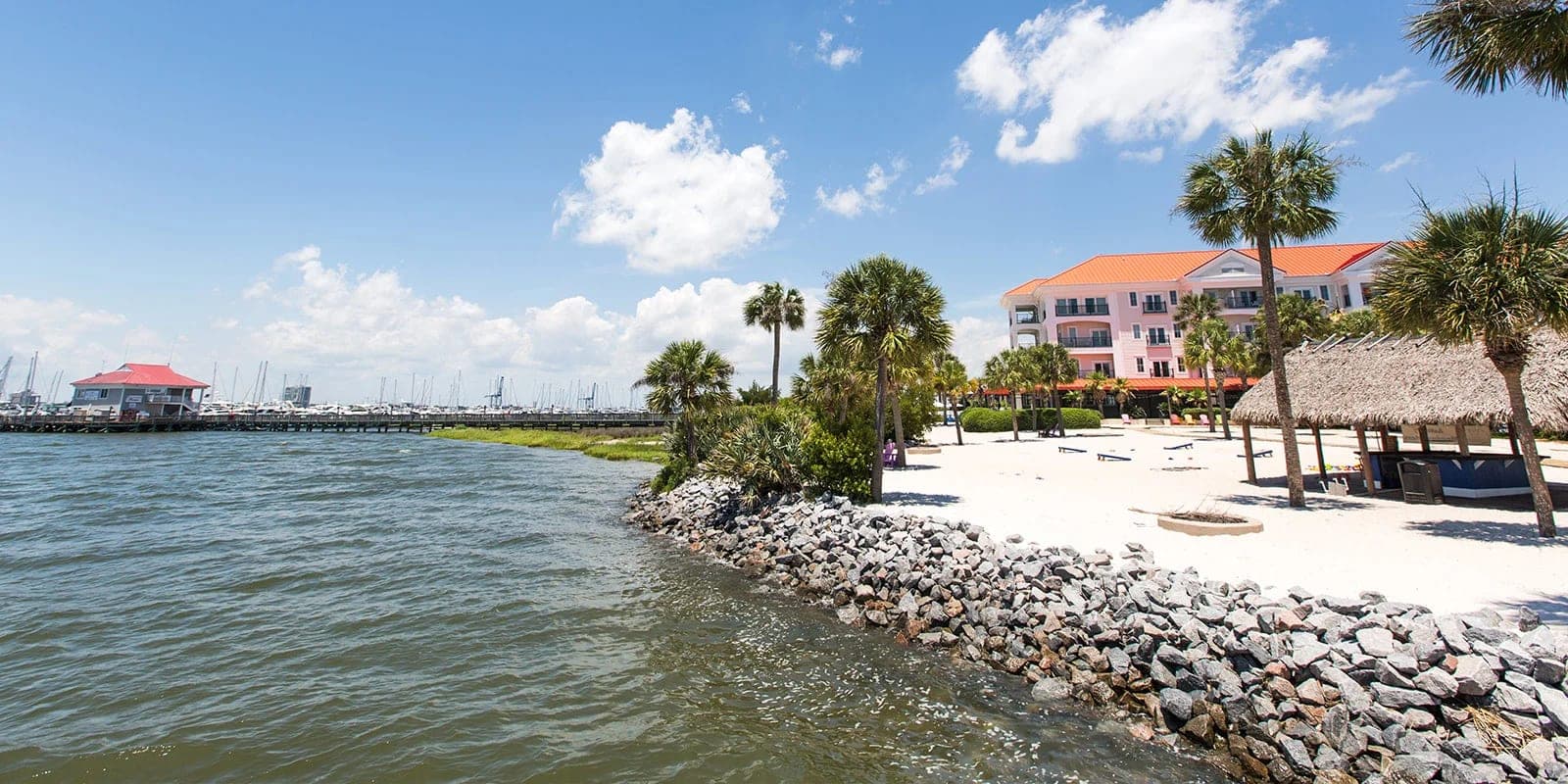 A beach with palm trees and a resort building by the water.