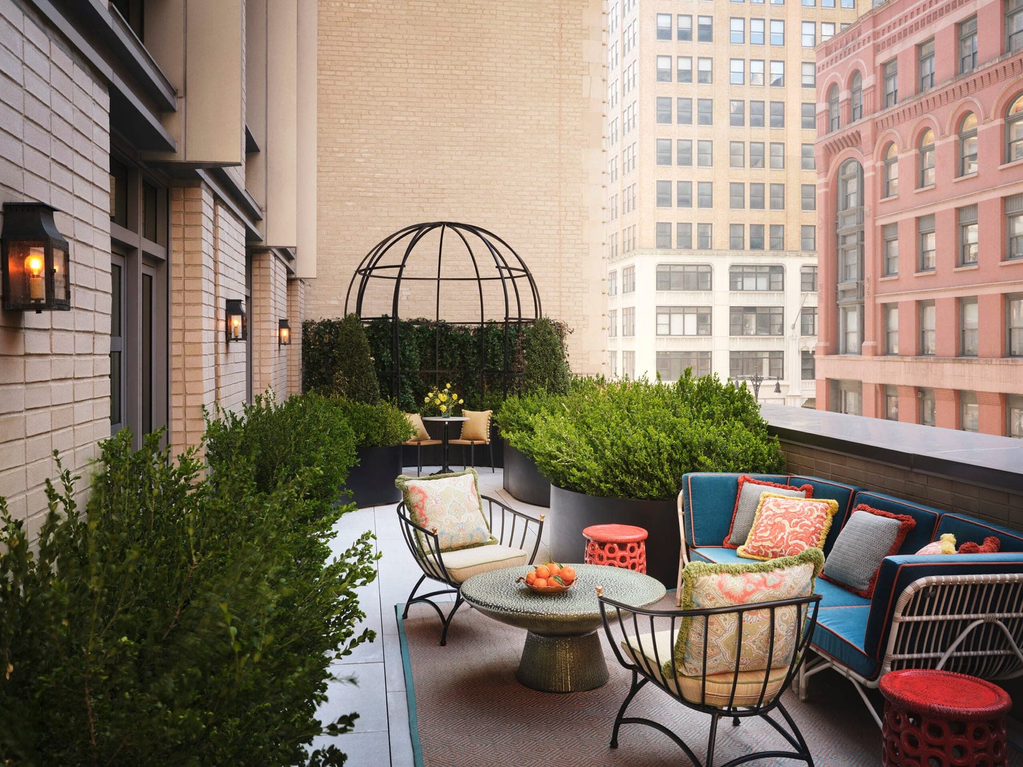 A New York City terrace with blue seating, tables, and greenery.