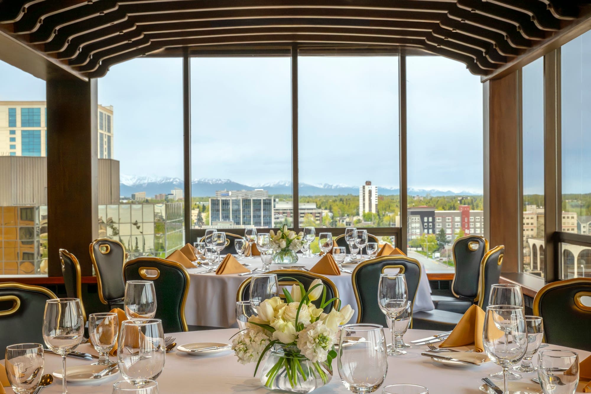 A dining table set for a wedding reception with a view of the city and mountains.