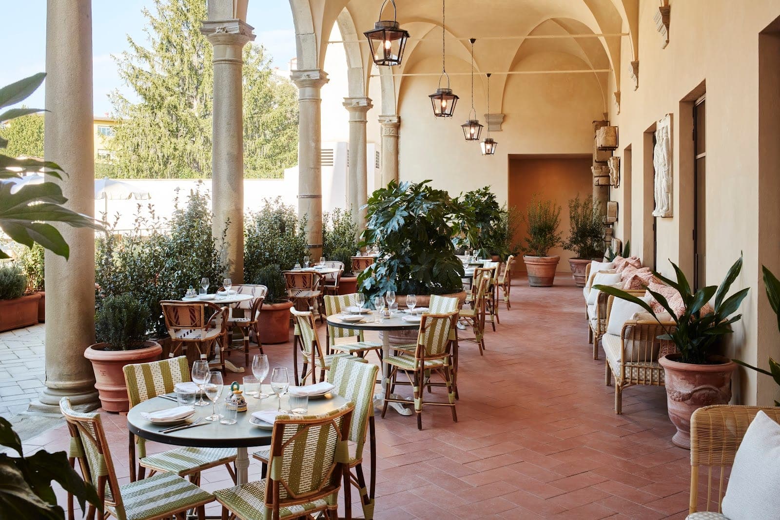 An outdoor covered dining area with tables and chairs set for a meal.