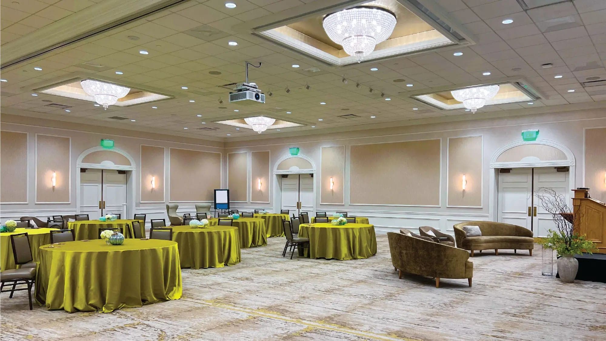 Banquet hall with round tables covered in yellow cloths and seating.