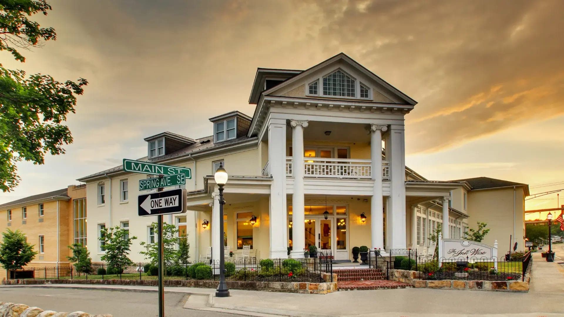 The Inn at Wise building exterior with columns and a balcony at dusk.