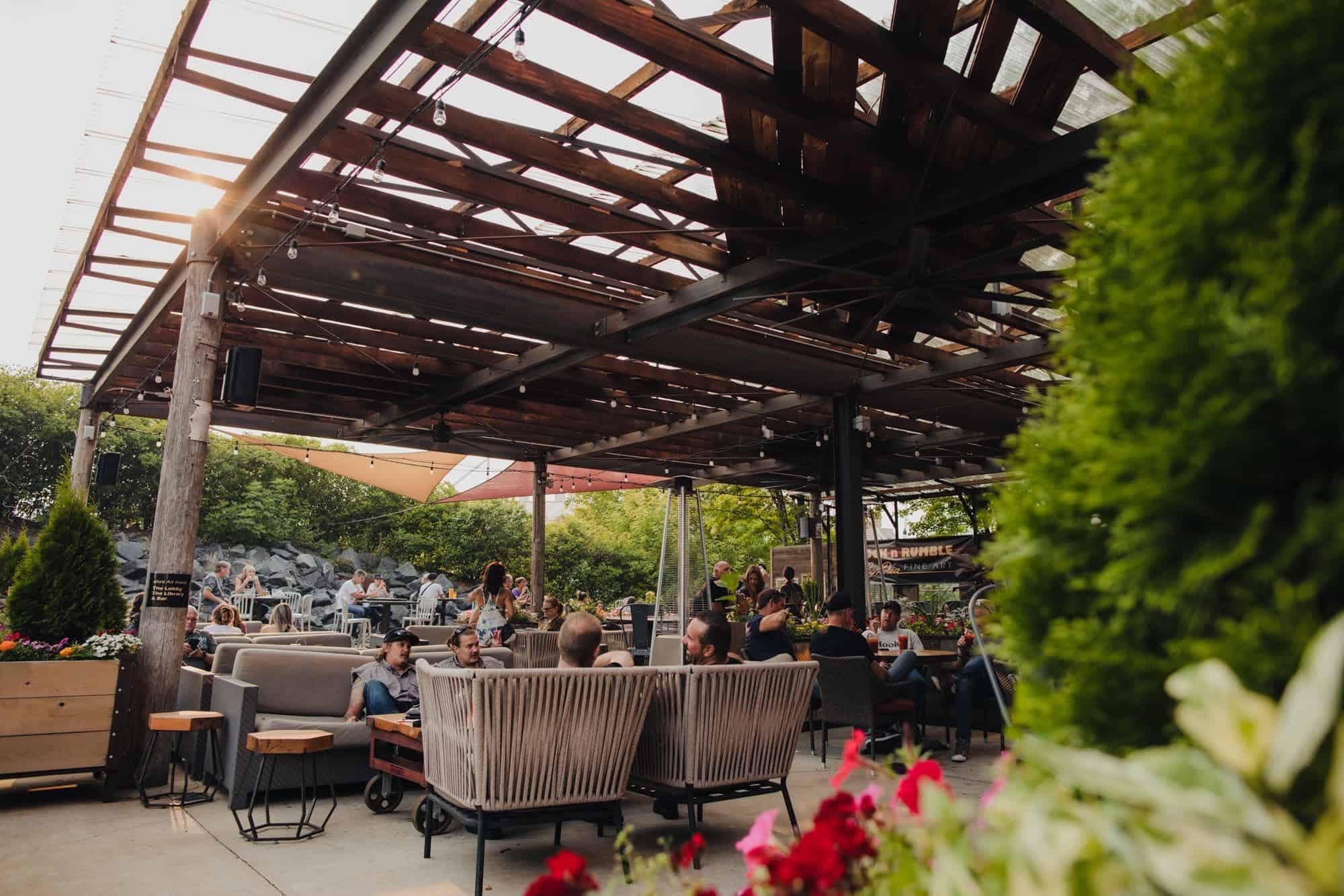 Outdoor seating area with a wooden roof and people relaxing.
