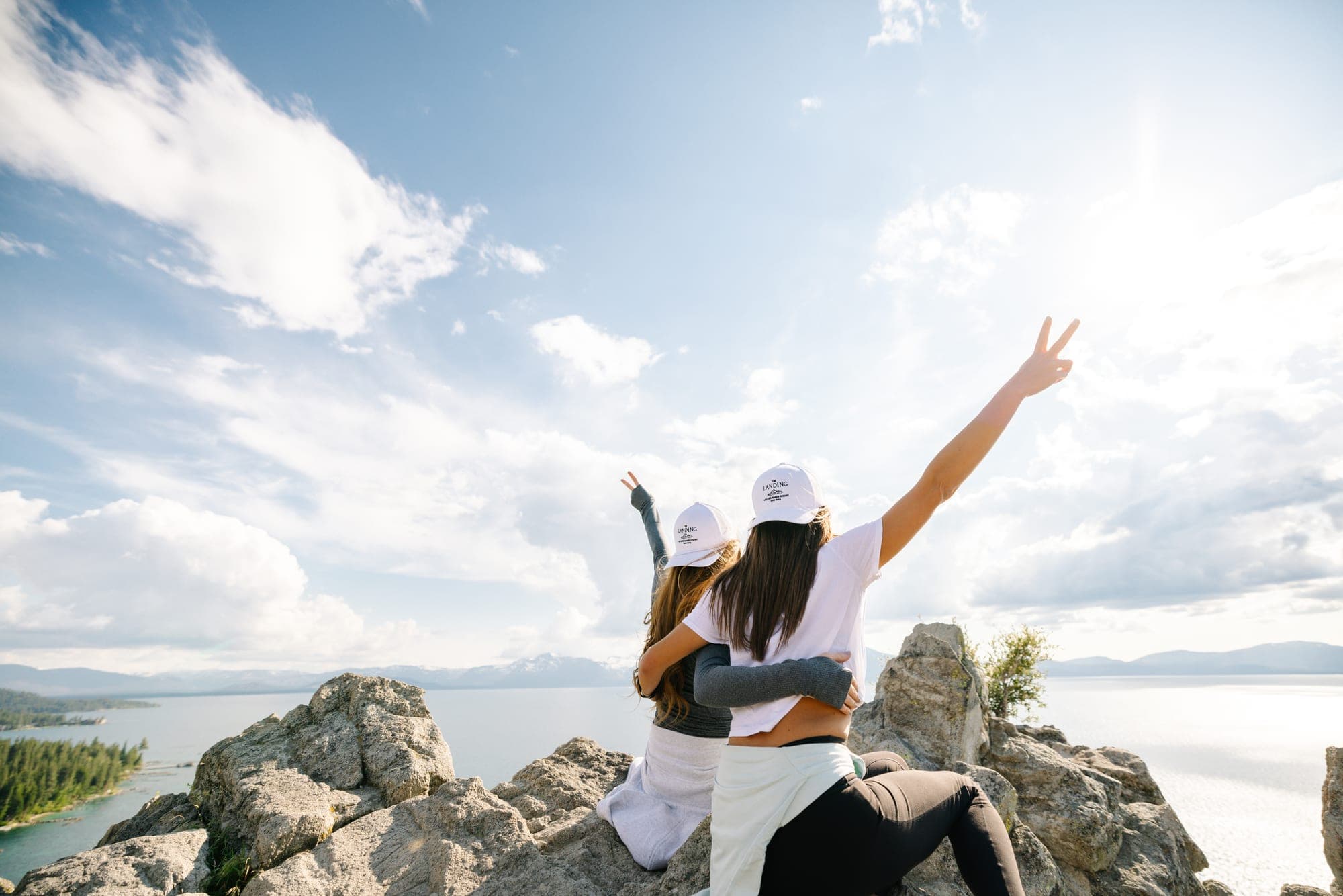 Two people on a rocky outcrop overlooking a lake.
