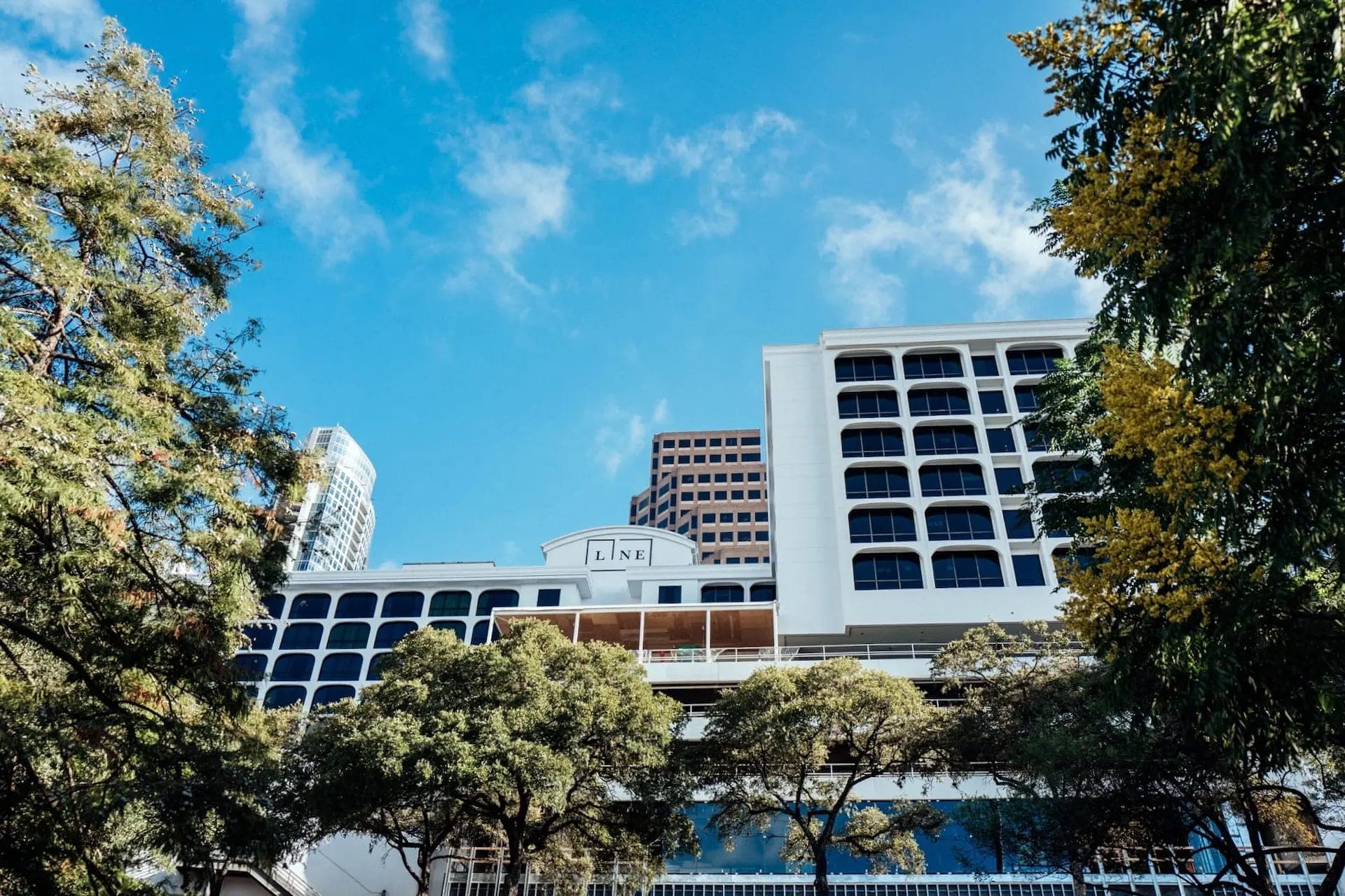 Exterior of The LINE Austin hotel with trees in the foreground and blue sky.