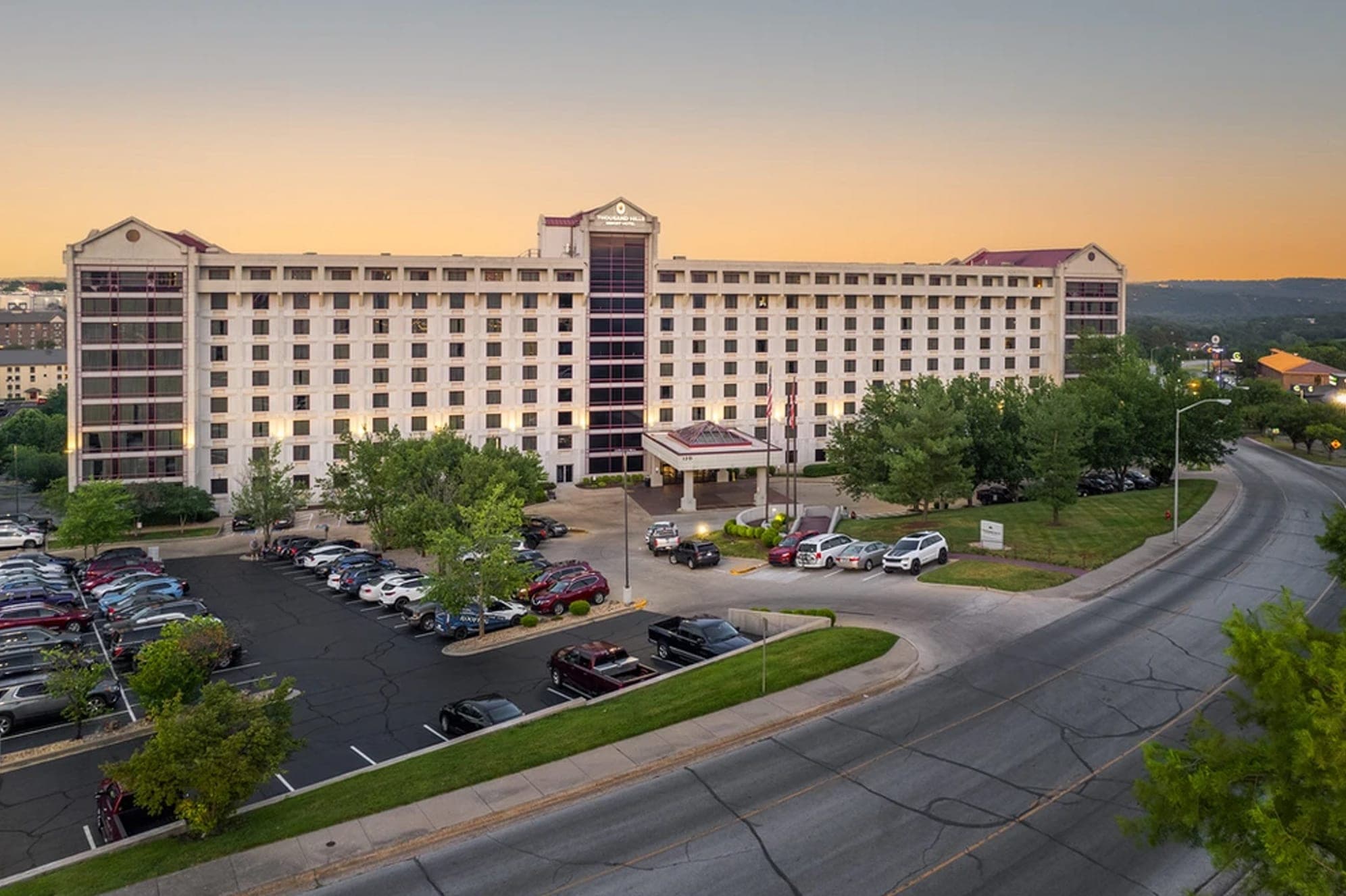 Exterior of a large hotel building with a parking lot and road.