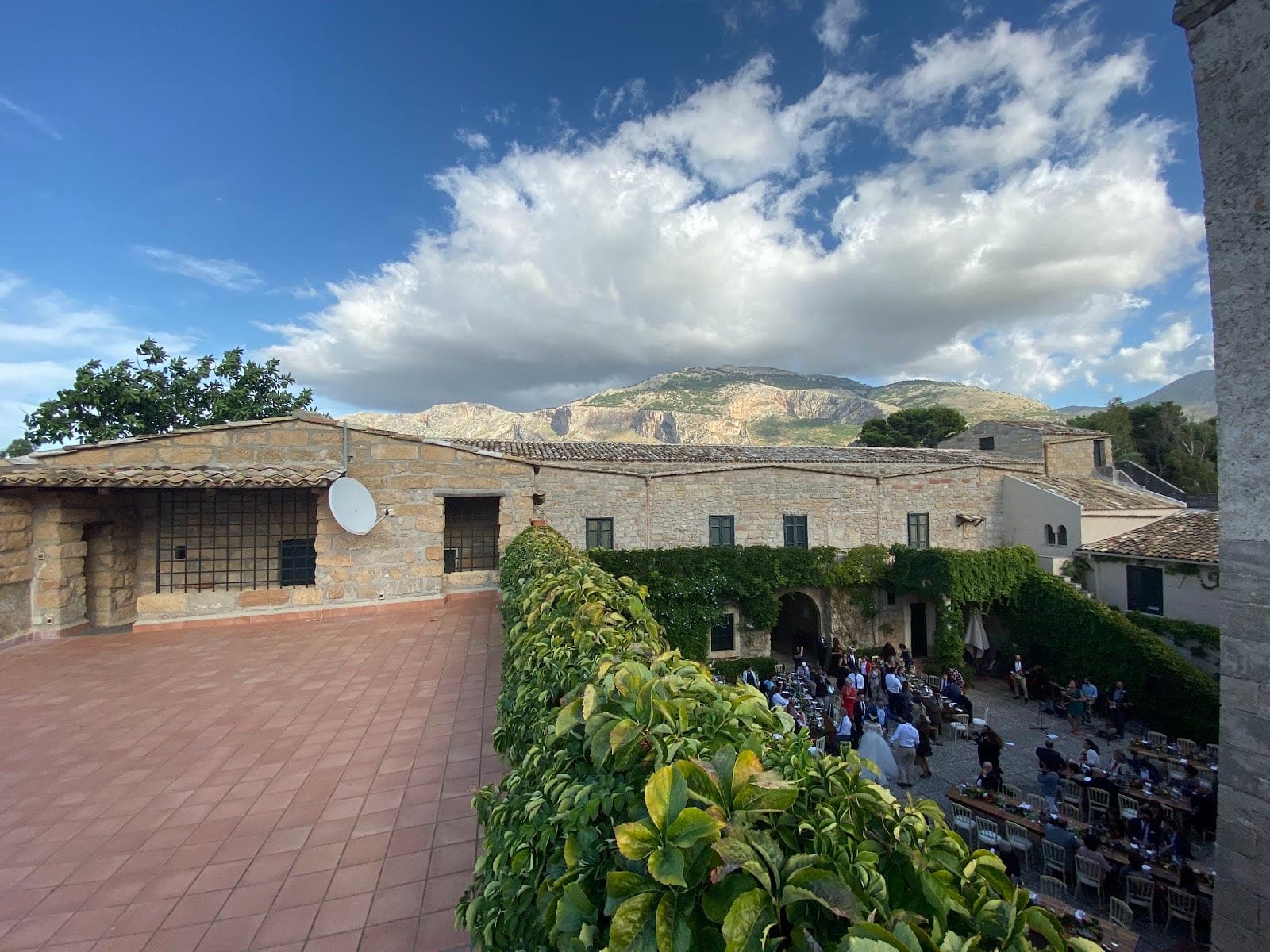 Courtyard with reception tables and guests, mountains in the distance.
