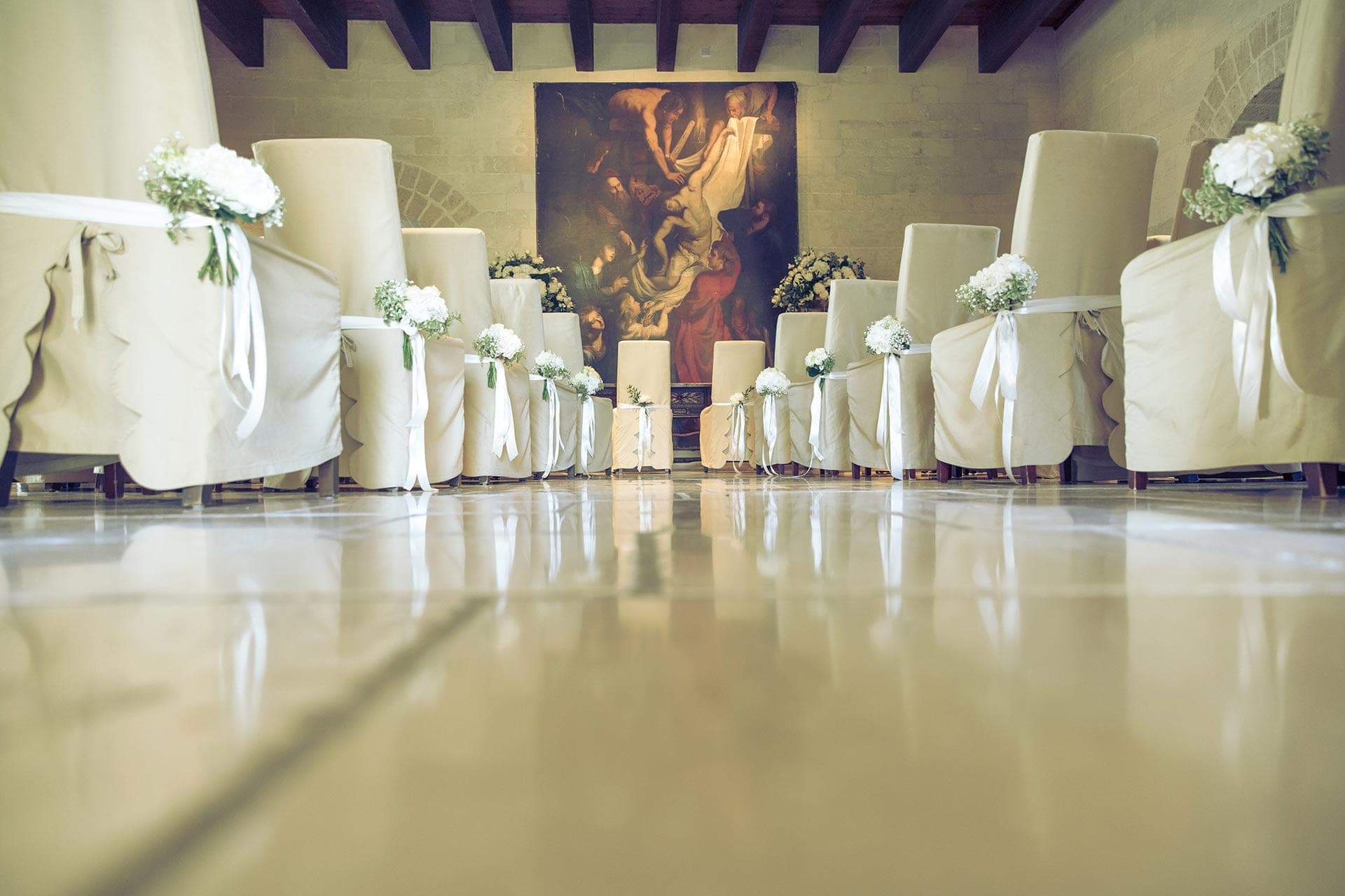 Chairs decorated with flowers and ribbons for a wedding ceremony.