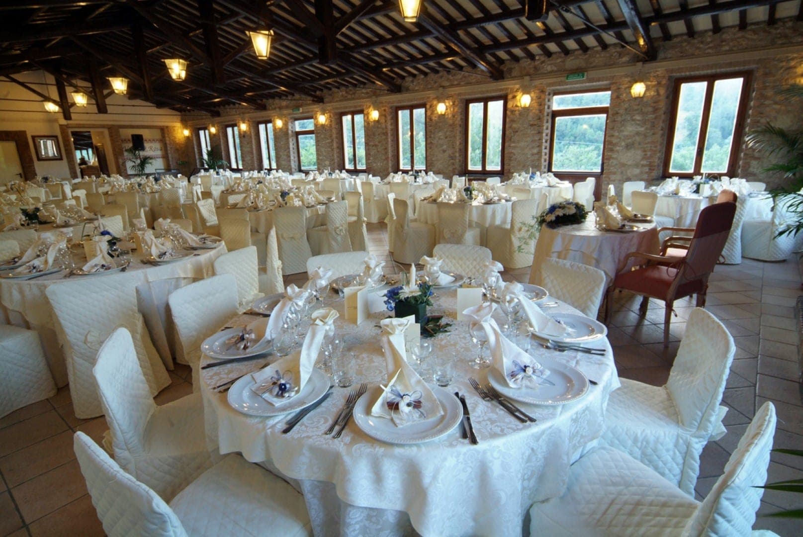 A wedding reception room with many tables set for guests.