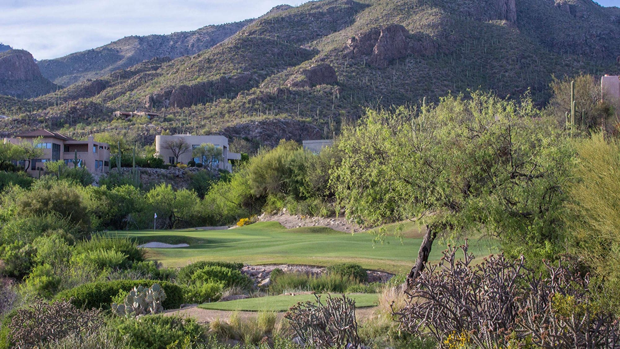 A golf course with buildings and mountains in the background.
