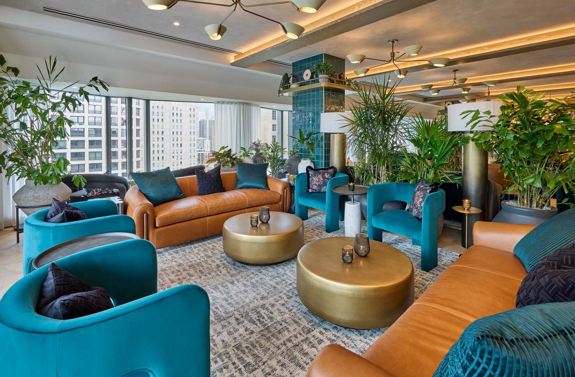A lounge area with teal chairs and a brown sofa around gold coffee tables.
