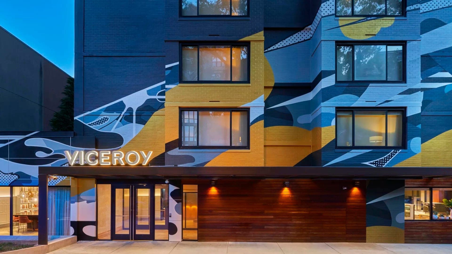 Exterior of the Viceroy hotel with a large mural and illuminated sign.