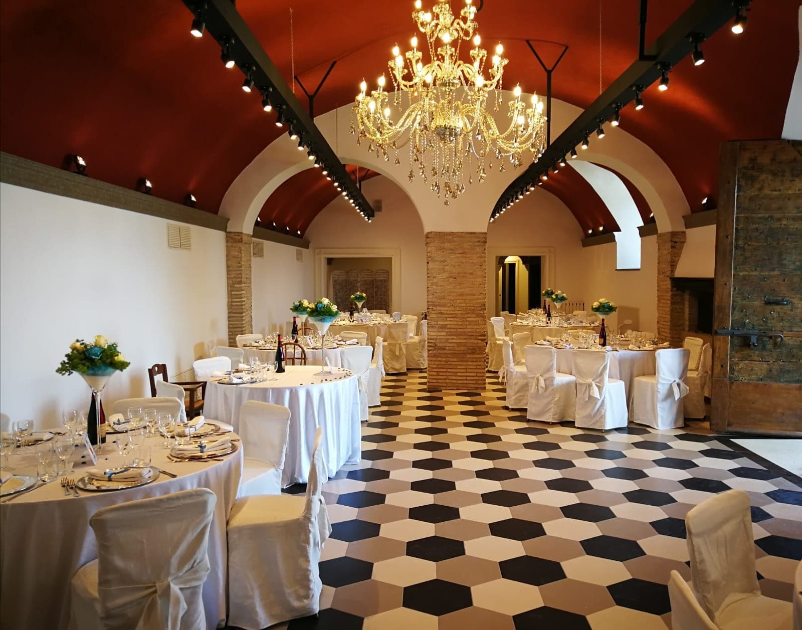 A reception room with round tables covered in white tablecloths and white chairs.