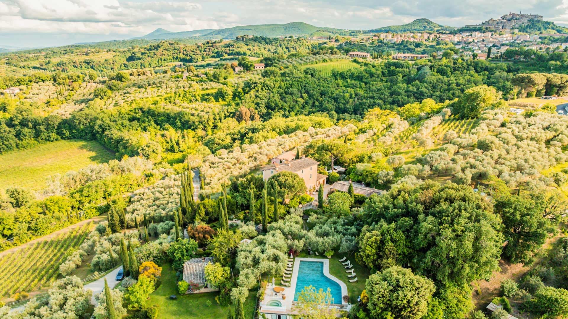 Aerial view of Villa Cicolina with a swimming pool and surrounding Tuscan landscape.