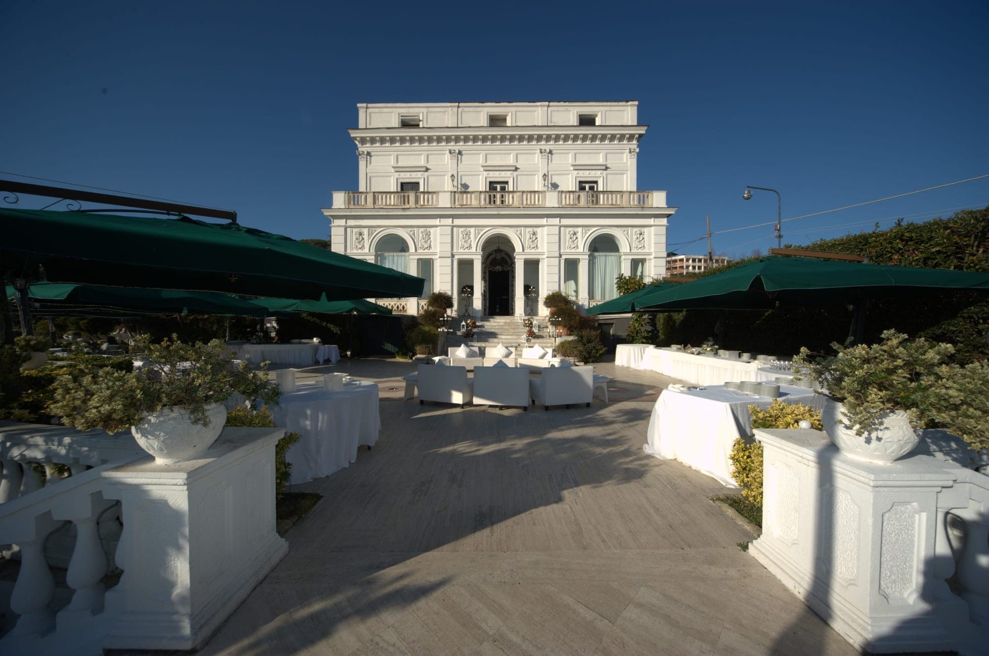 White building with outdoor seating and tables set for an event.