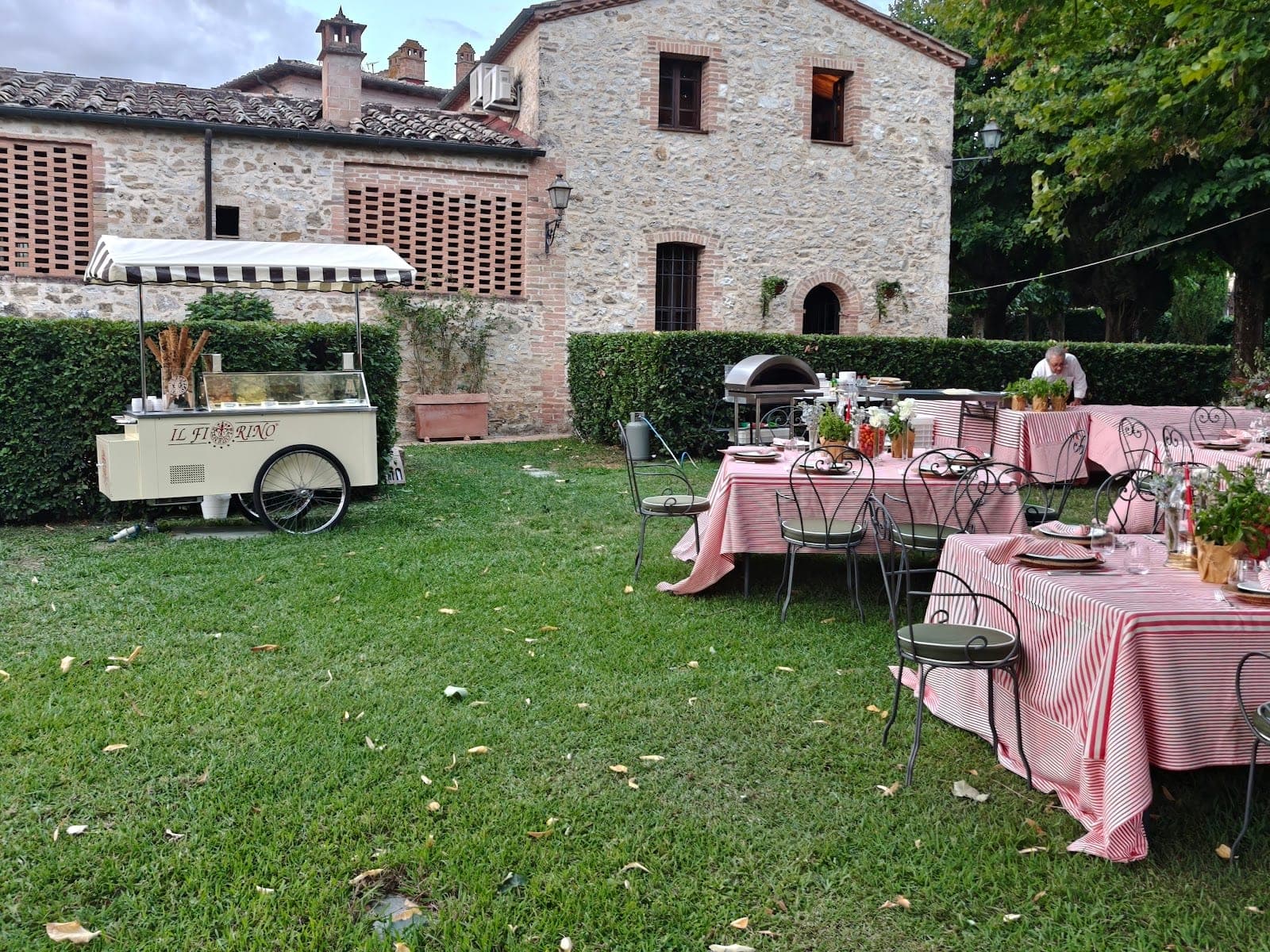 Outdoor reception tables with red and white striped cloths and an ice cream cart.