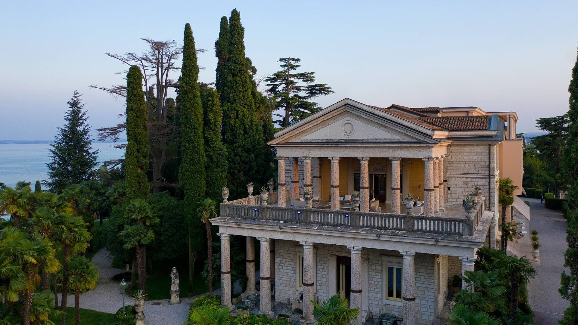 Exterior of Villa Cortine with columns, balcony, and lake view.