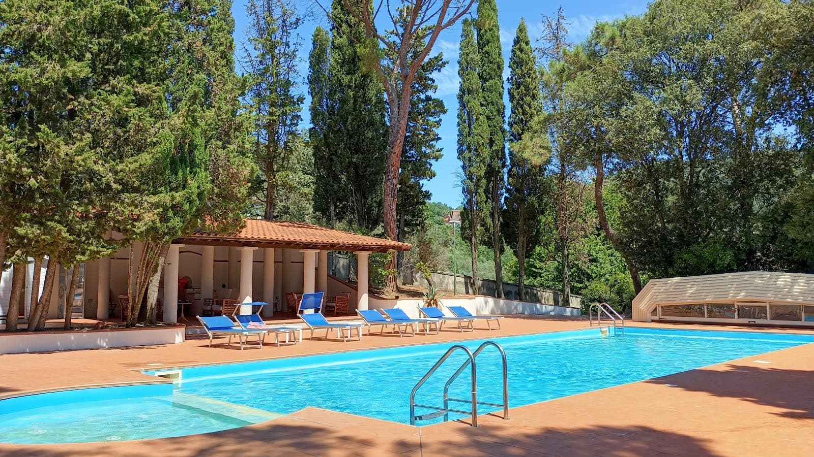 Swimming pool with lounge chairs and a covered seating area at a venue.