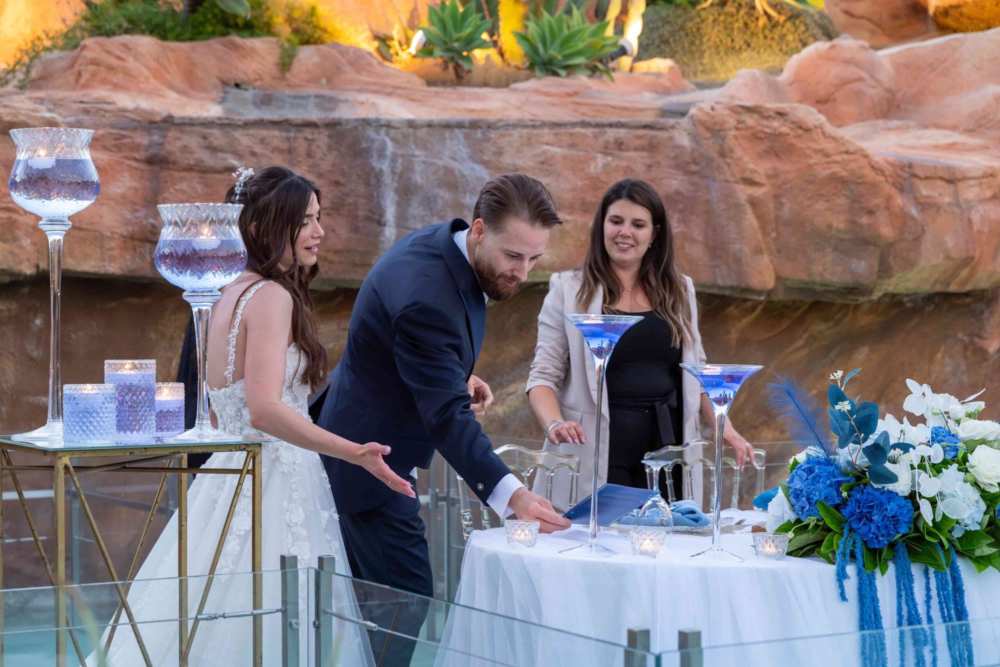Bride and groom at a wedding ceremony table with blue floral arrangements.