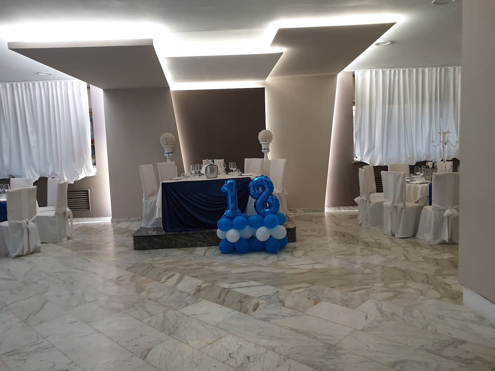 A reception room with tables set for an event and balloons.