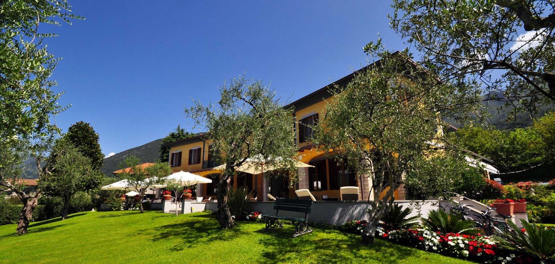 Exterior of Villa Kinzica with a green lawn and trees under a blue sky.