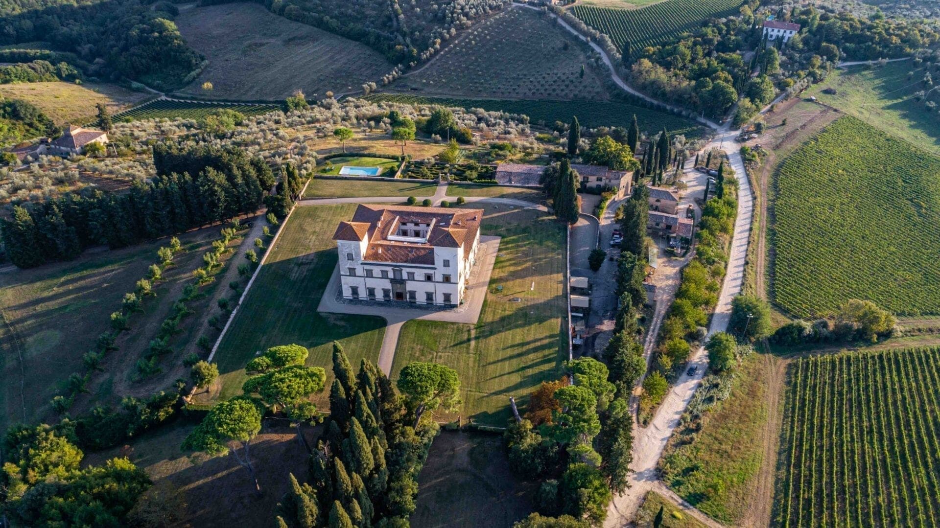 Aerial view of Villa Le Corti surrounded by vineyards and gardens.