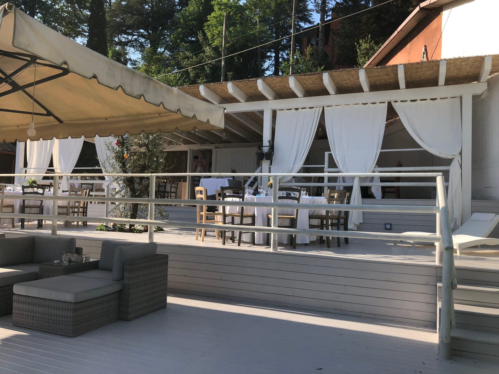 Outdoor reception area with tables set for dining under a covered patio.