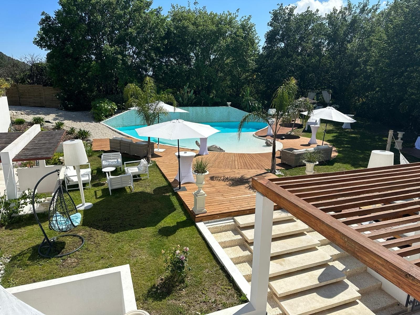Outdoor area with a swimming pool, wooden deck, umbrellas, and seating.