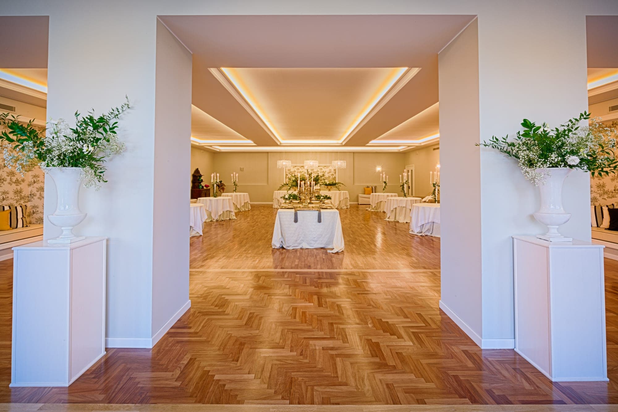 A reception room with tables set for a wedding, viewed from a hallway.