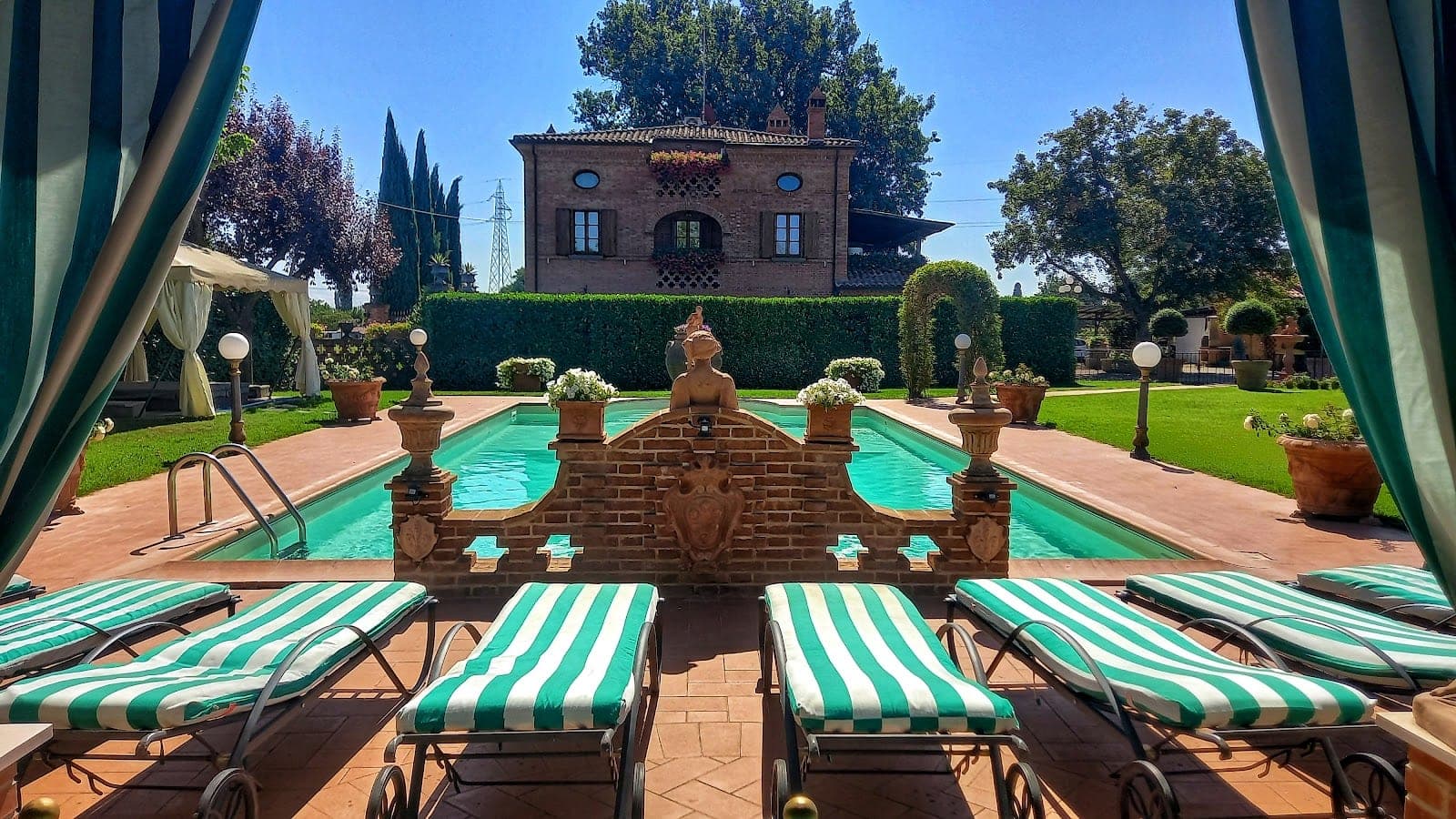 Swimming pool with lounge chairs and a villa in the background.