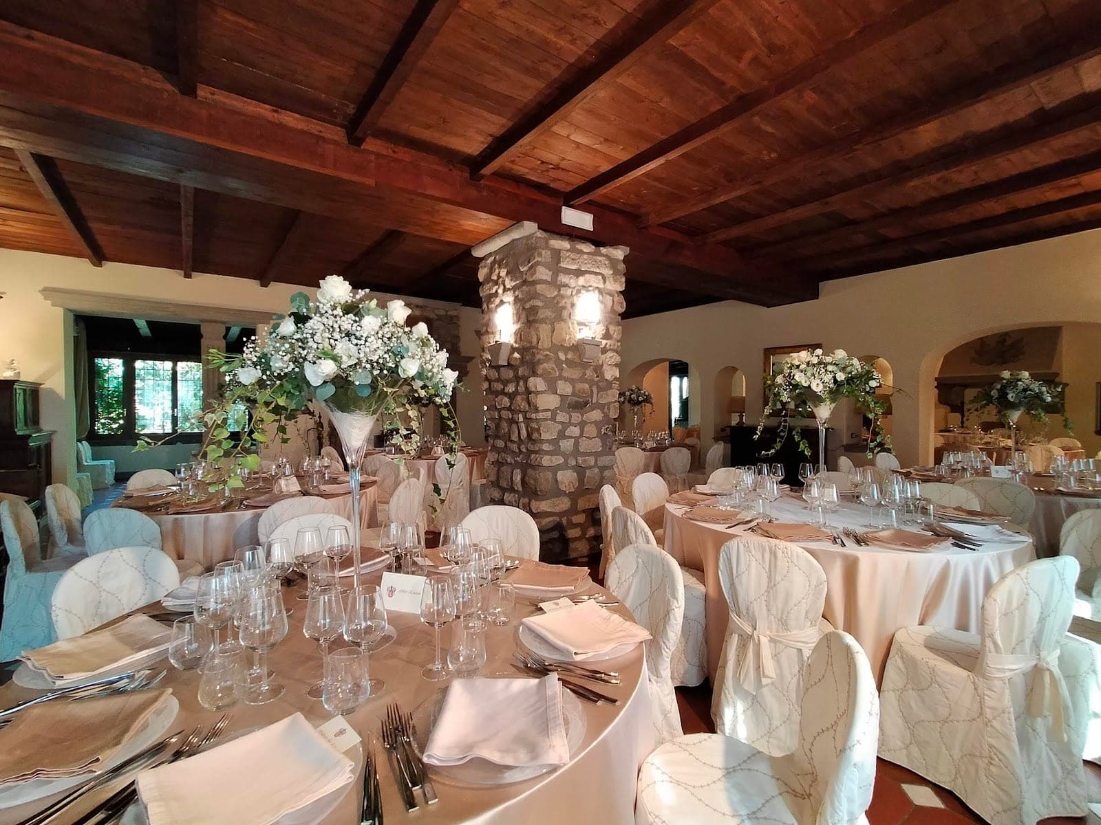 A reception table set with white linens, glassware, and floral centerpieces.