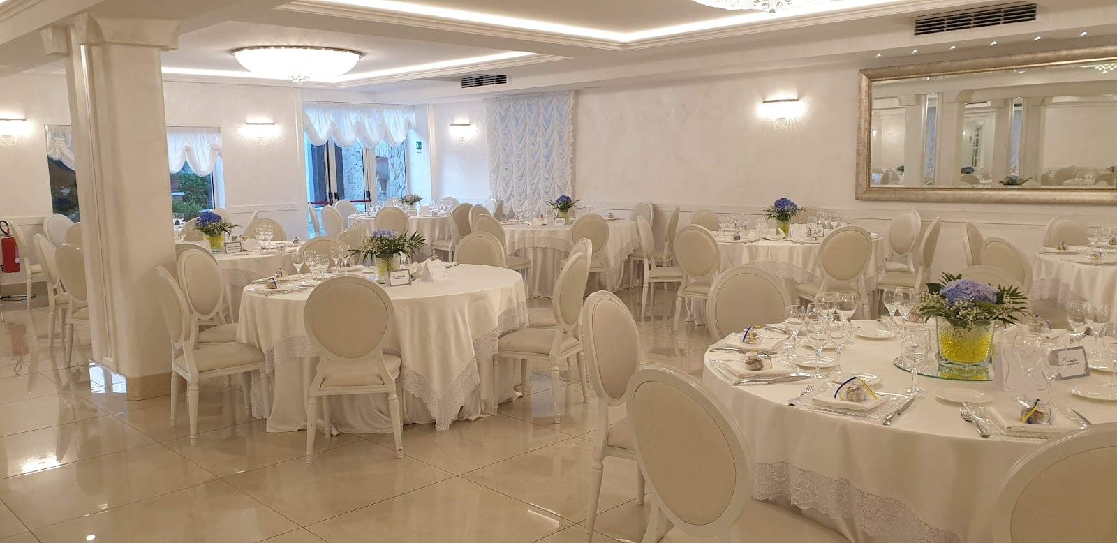 A reception room with round tables set for a wedding meal.