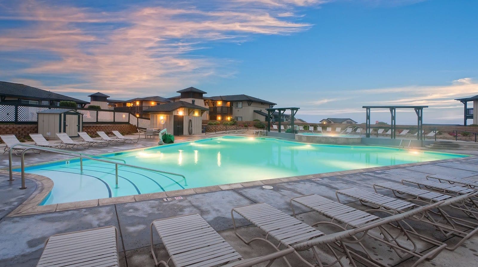 Swimming pool and lounge chairs at dusk with venue buildings in the background.
