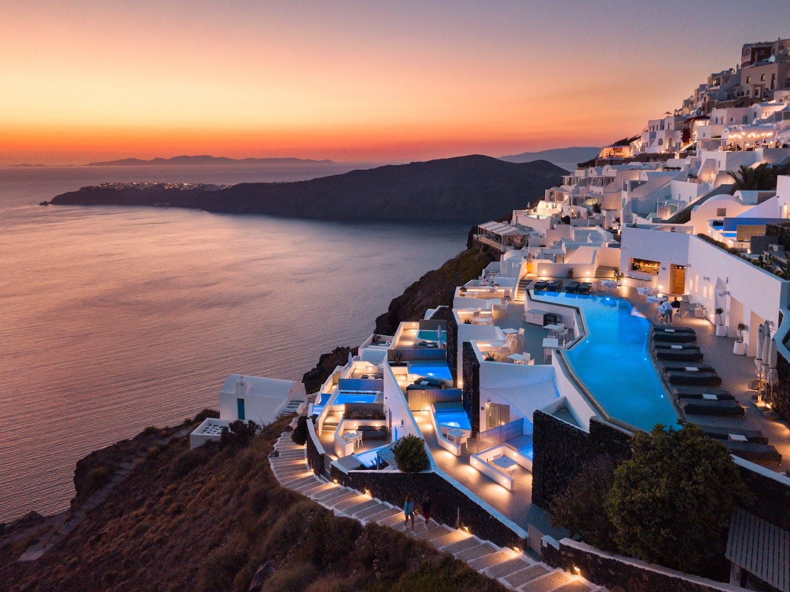 The caldera-edge pool terrace at Grace Hotel in Imerovigli, Santorini, at dusk
